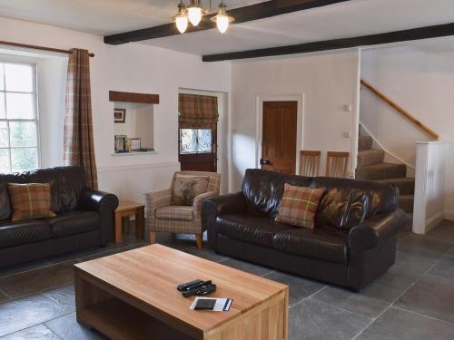 a living room with leather couches and a coffee table at Acorn Lodge Cottage in Keswick