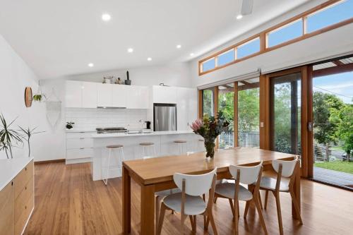 una cucina con un tavolo in legno e mobili bianchi di Jan Juc Coastal Retreat 500m to Beach Pet Friendly a Torquay
