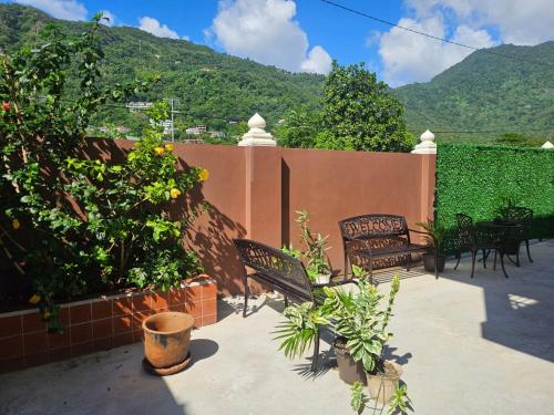 a patio with chairs and a fence with mountains in the background at Agape Suites-Room 1- Ground Floor in Soufrière
