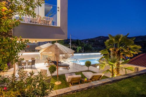 a villa with a swimming pool and a patio with tables and chairs at Aigli Skala Maries Deluxe in Skala Marion