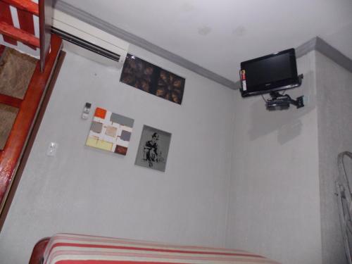 a room with a tv on the wall and a couch at Léa Pousada in Fortaleza