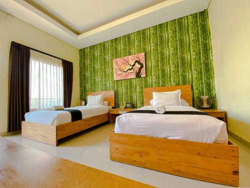 ラブハン・バジョにあるExotic Komodo Hotelのベッドが2つあり、緑の壁紙が貼られた寝室