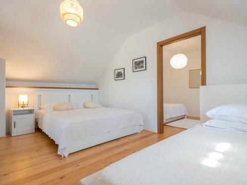 a white bedroom with two beds and a mirror at Green Paradise with pool in Dropuljići