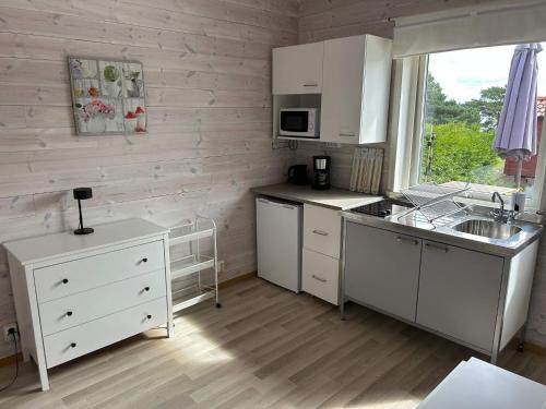 a kitchen with white cabinets and a sink and a window at 6 person holiday home in SVANESUND in Buvik