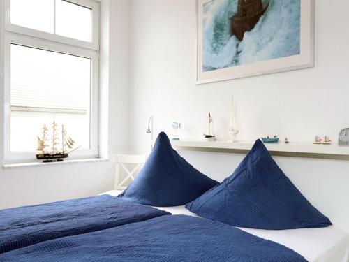 a bed with blue pillows in a white bedroom at Residence at the Spa Park 2 in Warnemünde