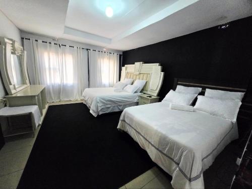 a hotel room with two beds and a window at Shado's residence self catering cotages in Serowe