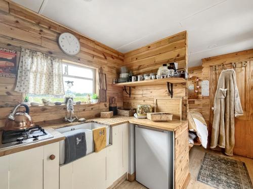 a kitchen with wooden walls and a clock on the wall at The Box - Oasis Farm in Fareham