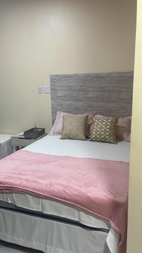 a bed with pink sheets and pillows on it at Quarto em Belém - Próximo ao Mercado de São Brás in Belém