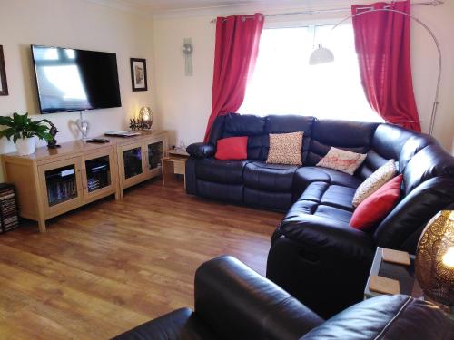 a living room with a leather couch and a television at Sweet Briar in Newquay