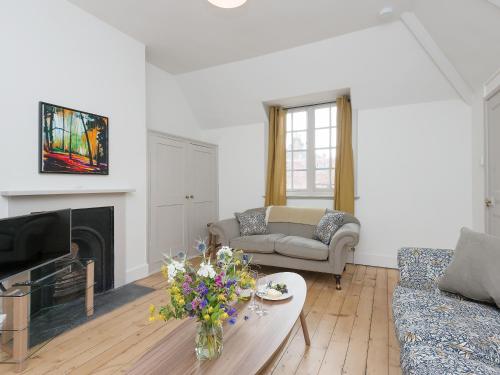 a living room with a couch and a fireplace at Stable Yard Cottage in Selborne