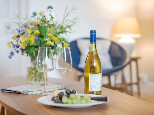 a bottle of wine on a table with wine glasses at Stable Yard Cottage in Selborne