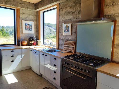 une cuisine avec des armoires blanches et un four à plaques de cuisson dans l'établissement Pikikirunga House, Takaka Hill, à Upper Takaka