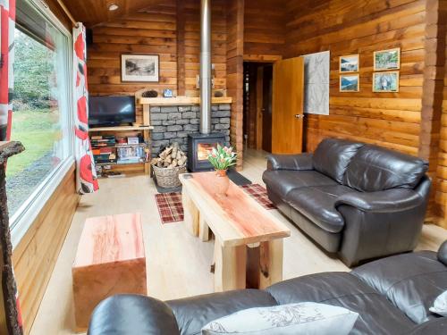 a living room with leather furniture and a fireplace at Ard Darach Lodge in Dunoon