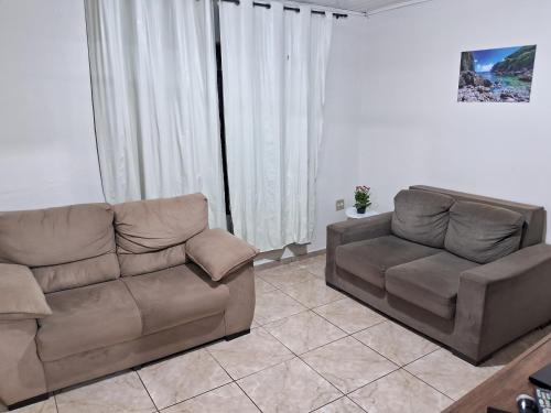 una sala de estar con un sofá y una silla en Quartos Morumbi, en Foz do Iguaçu