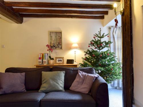 ein Wohnzimmer mit einer Couch und einem Weihnachtsbaum in der Unterkunft The Old Sweet Shop in Hook Norton