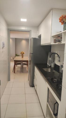 a kitchen with white cabinets and a table with a dining room at Apartamento Aconchegante e completo em Manaíra in João Pessoa