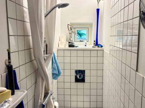 a white tiled bathroom with a sink and a shower at 6 person holiday home in Hasle in Rønne