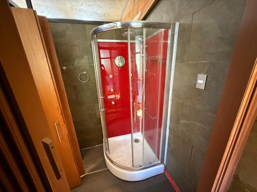 a glass shower in a bathroom with a red wall at Loft acogedor en el campo in Putaendo