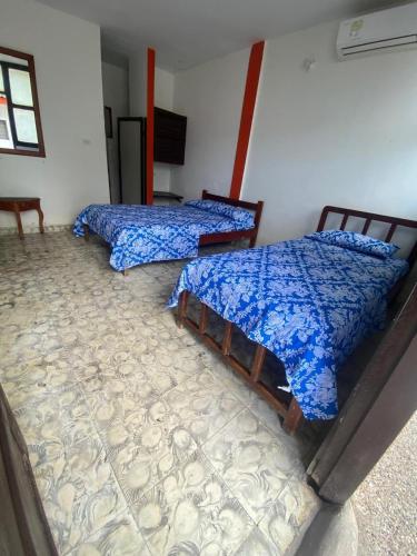 two beds sitting in a room with a floor at Hotel Los Nogales Coveñas in Coveñas