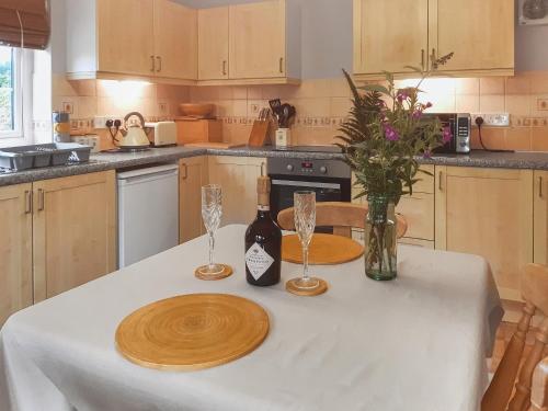 Mount HawkeにあるThe Old Dairyの2本のボトルとグラスが置かれたテーブルのあるキッチン