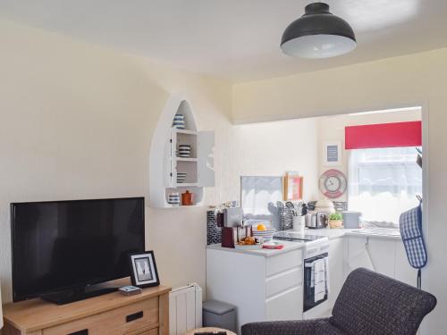 a living room with a tv and a kitchen at Escape To The Chalet in Pakefield