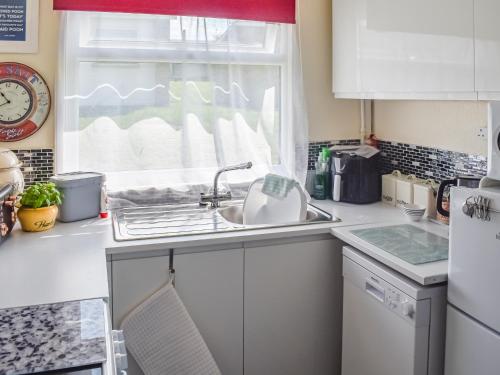 a kitchen with a sink and a window at Escape To The Chalet in Pakefield