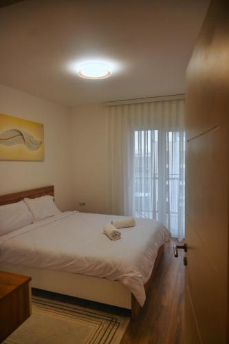 a bedroom with a white bed and a window at Sweet Dreams Apartment in Prishtinë