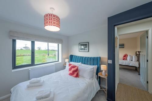 a bedroom with a white bed and a window at Petryal in Llangernyw