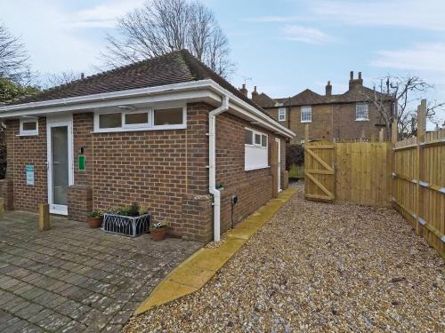 a brick house with a gate and a fence at The Secret Luxury Apartment in New Romney