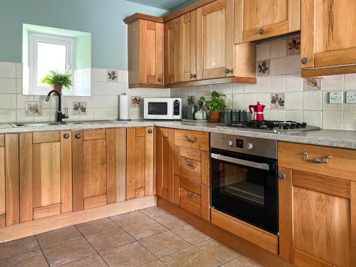 a kitchen with wooden cabinets and a stove and microwave at Mushroom Cottage in Ferndale