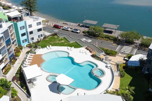 eine Luftansicht auf einen großen Pool neben dem Meer in der Unterkunft Seaside Solace at Caloundra Seaview 3BD Apartment in Caloundra