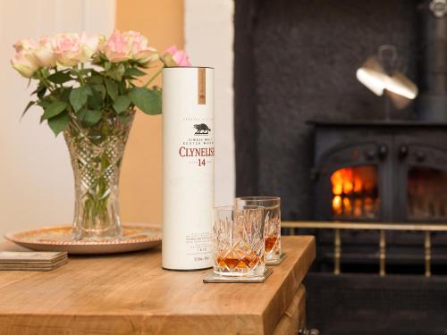 einen Tisch mit einer Vase Blumen und einer Flasche Wein in der Unterkunft Big Barns Cottage in Backies