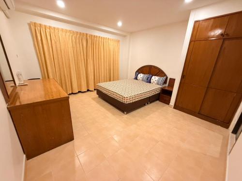 Un dormitorio con una cama y una cómoda en una habitación. en Jasmine Villa Soi Buakhao, en Pattaya central