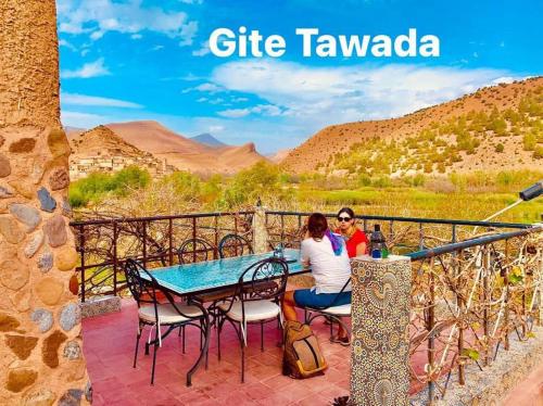 Dos personas sentadas a una mesa en un patio con vistas a las montañas en Hôtel Tawada, en Azilal