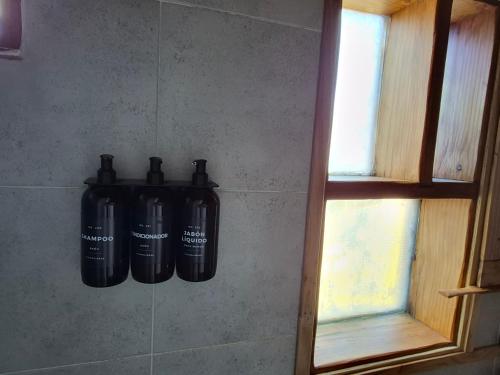 a group of black bottles hanging on a wall at KUNTUR 2 Cabañas in El Chalten