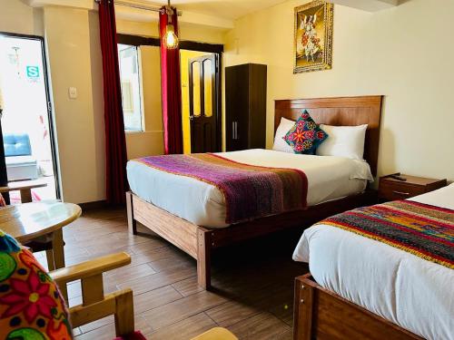 a hotel room with two beds and a table at ECOTERRA-SAN FRANCISCO Cusco in Cusco
