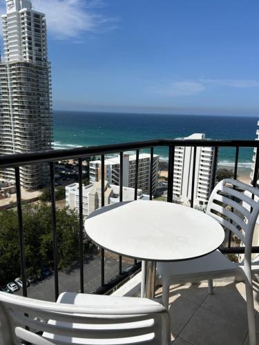 een witte tafel en stoelen op een balkon met uitzicht op de oceaan bij Mantra on View in Gold Coast