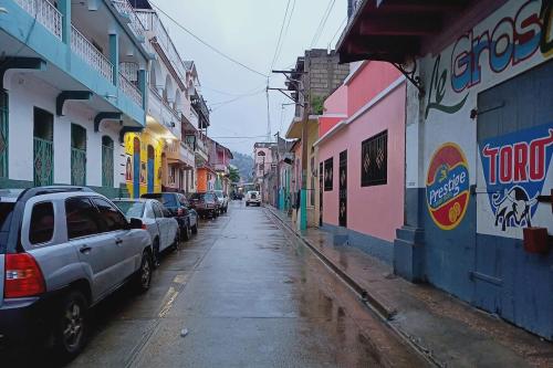 a city street with cars parked on the sidewalk at Auberge du Gouverneur, Rue 13-14J, Cap-Haitien, Haiti in Cap-Haïtien