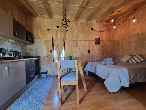 a kitchen and a bedroom with a bed and a table at KUNTUR 2 Cabañas in El Chalten