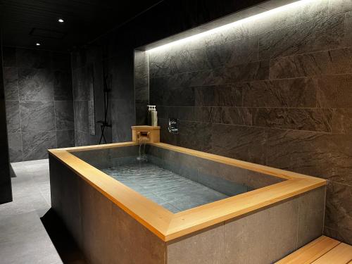 een badkuip in een kamer met een stenen muur bij soyo-ka kyoto sanjo in Kyoto