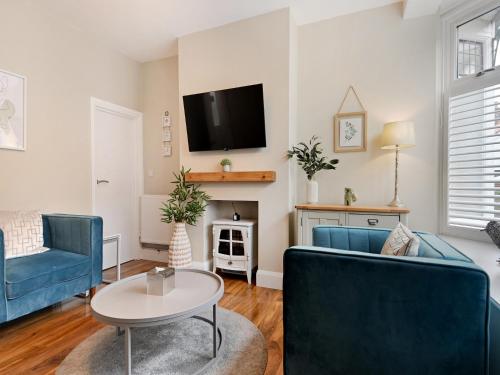 a living room with two blue chairs and a tv at Beaconsfield House in Mundesley