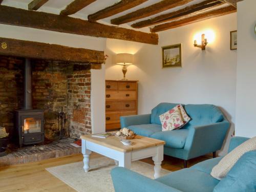 a living room with a blue couch and a fireplace at Three Ash Cottage in Bungay