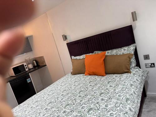 a bedroom with a bed with an orange pillow at WBC R4 - Private Studio Room in Bilston