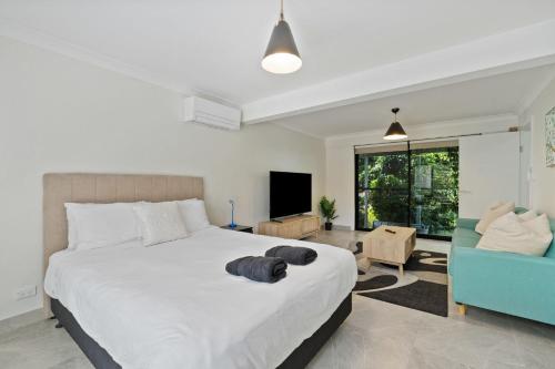 a bedroom with a large white bed and a blue chair at Misty Haven at Wentworth Falls in Wentworth Falls