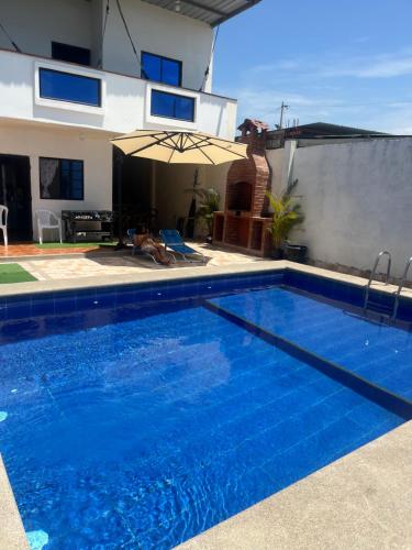 a swimming pool with an umbrella next to a house at Casa en playas in Playas