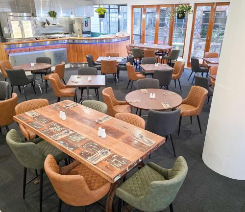 a restaurant with tables and chairs and a kitchen at Distinction New Plymouth Hotel in New Plymouth