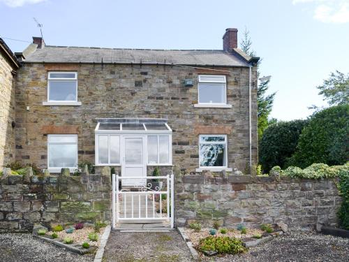 a brick house with a gate in front of it at Ling Farm Cottage in Holmewood