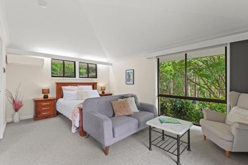 a bedroom with a bed and a couch and a chair at Tamborine Mountain Lodge in Mount Tamborine