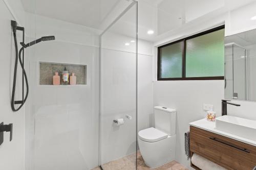 a white bathroom with a toilet and a sink at Tamborine Mountain Lodge in Mount Tamborine