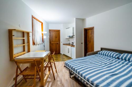 a bedroom with a bed and a desk and a kitchen at Cervinia Ski In Ski Out - Peak Studio in Breuil-Cervinia